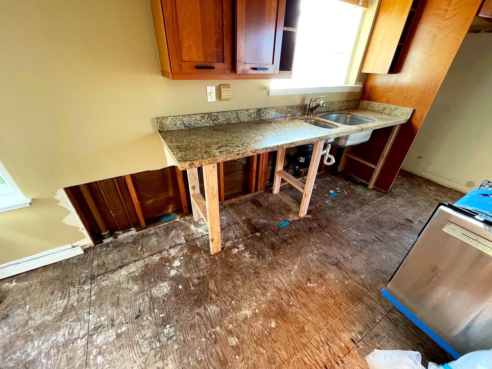 Kitchen sink supported above exposed subfloor after cabinet removal