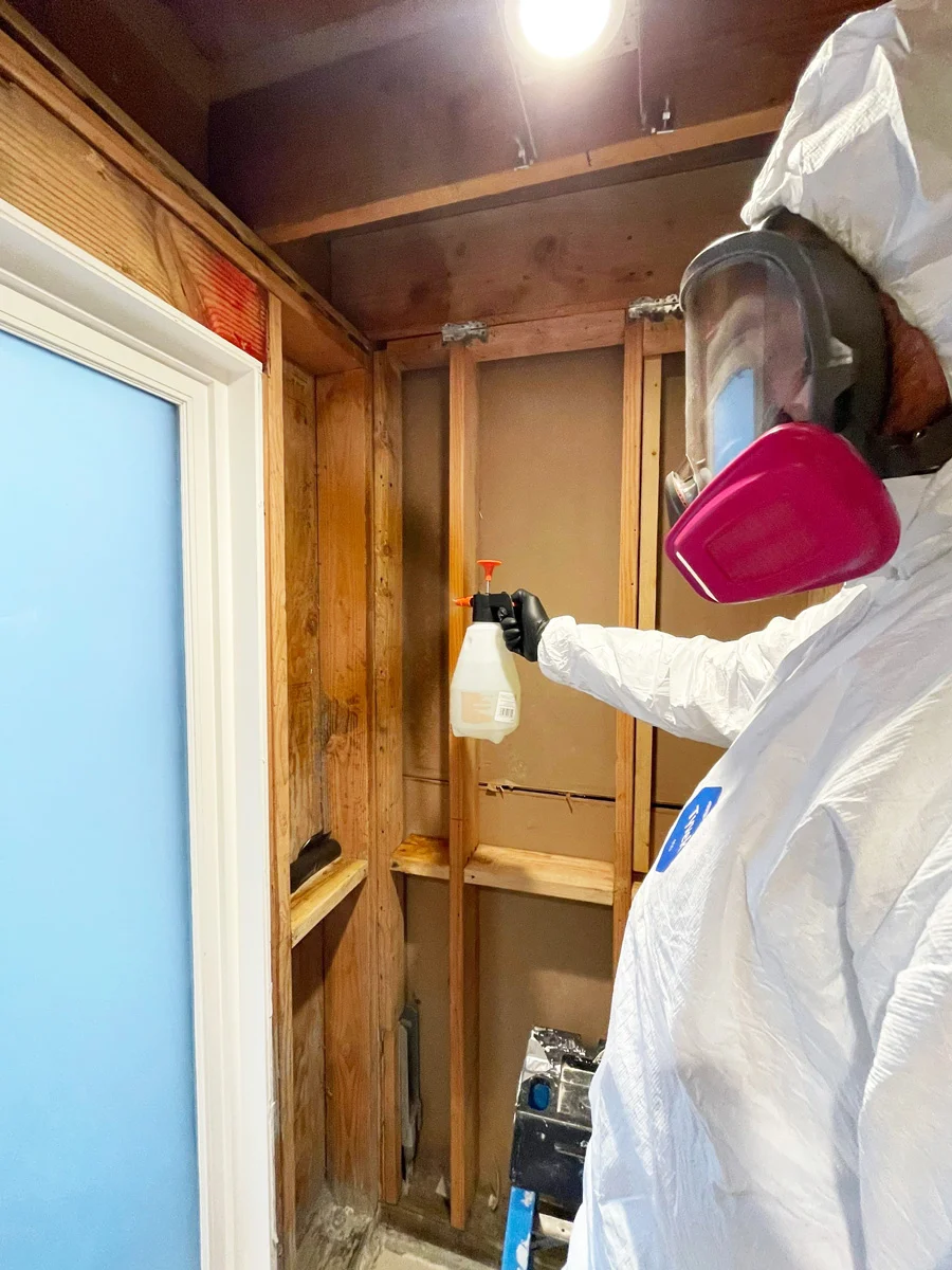 Technician in a respirator treating exposed wall framing — San Francisco, CA