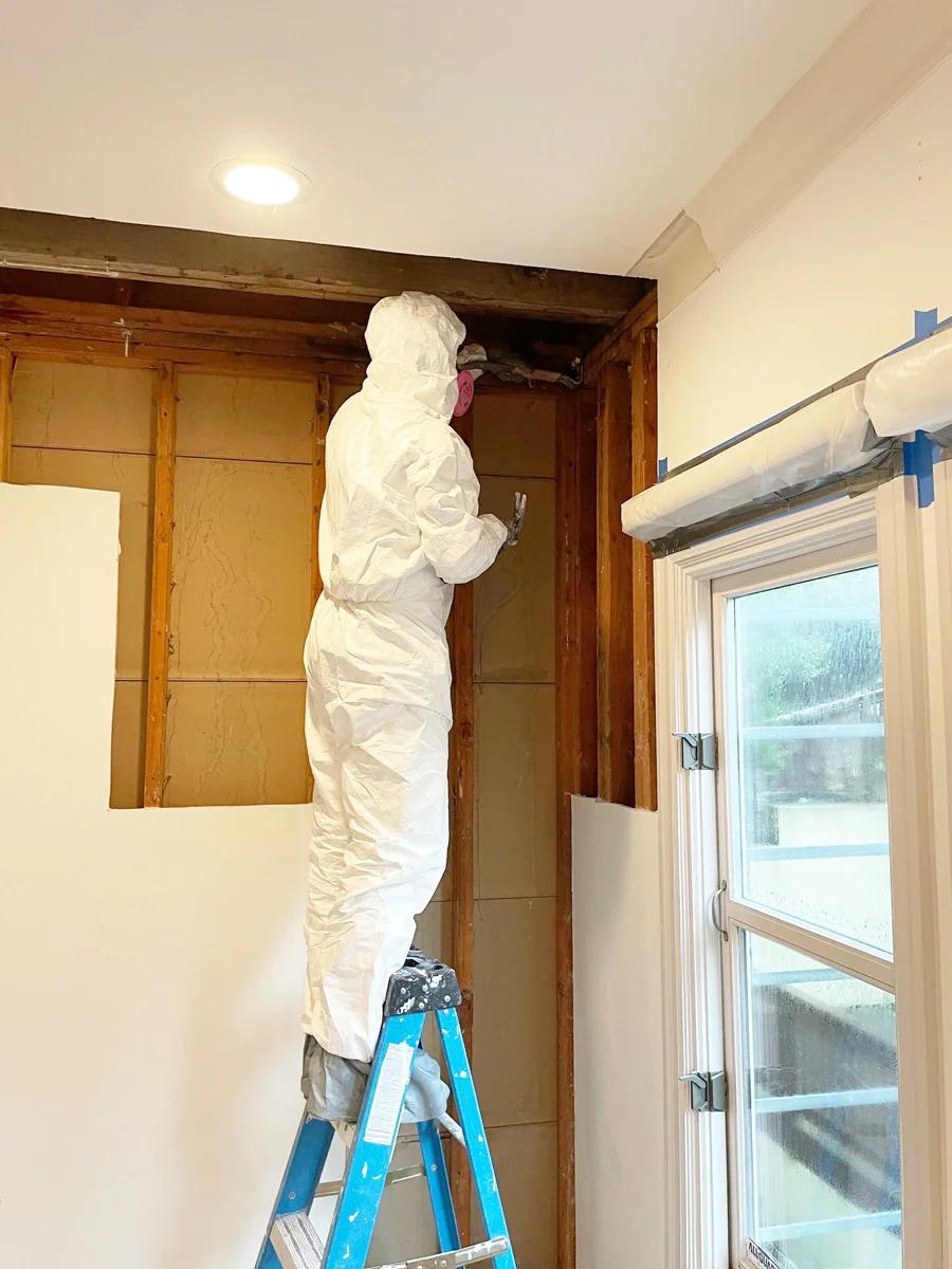 Technician removing upper-wall drywall from a ladder — San Francisco, CA