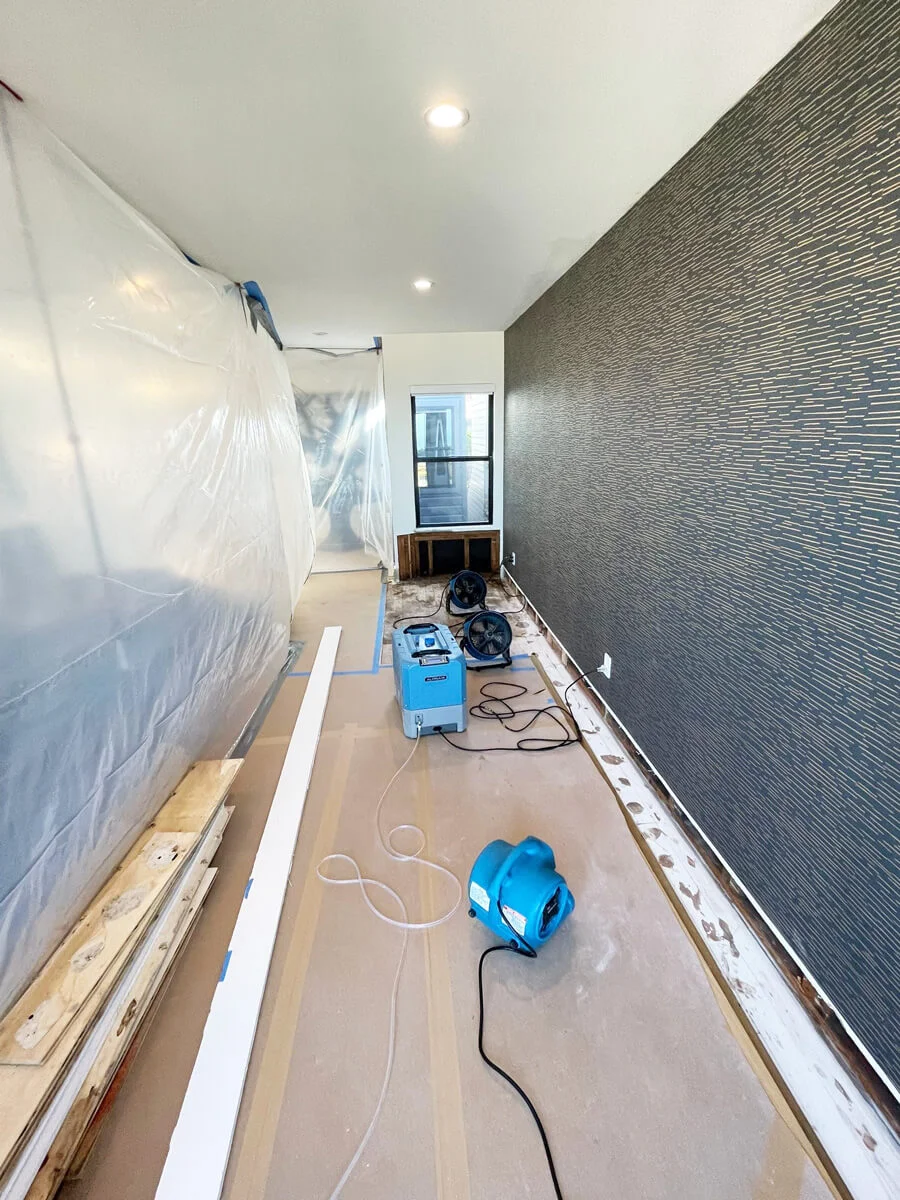 Air movers drying exposed flooring beside a textured wall — San Francisco, CA