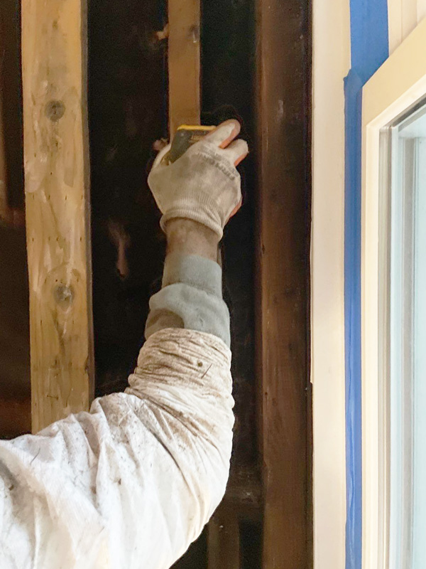 Gloved technician treating wood framing beside a window — San Francisco, CA